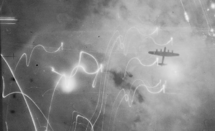 Die Silhouette eines britischen Bombers am Himmel über Hamburg im Juli 1943. Photograph C 3371 from the collections of the Imperial War Museums, Gemeinfrei